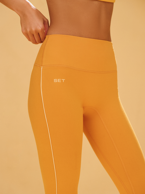 Mustard yellow leggings with a visible brand logo on a beige background