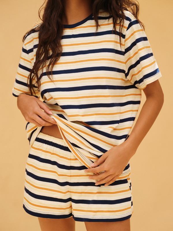 Person wearing a striped shirt and shorts set on a beige background