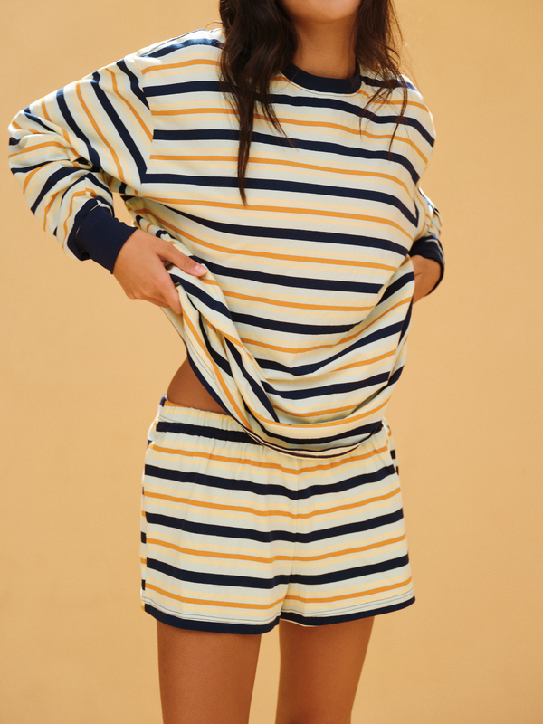 Person wearing a striped outfit with long sleeves and shorts on a beige background