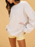 Person wearing a white oversized sweater with a graphic design on a beige background <model-info>Meeya wears a size XS and is 5’7, 23” waist, 32B bust.</model-info> 