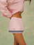 Person wearing a pink jacket and skirt with a logo on a green background <model-info>Meeya wears a size XS and is 5’7, 23” waist, 32B bust.</model-info> 