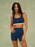 Woman wearing a blue sports bra and shorts set on a green background