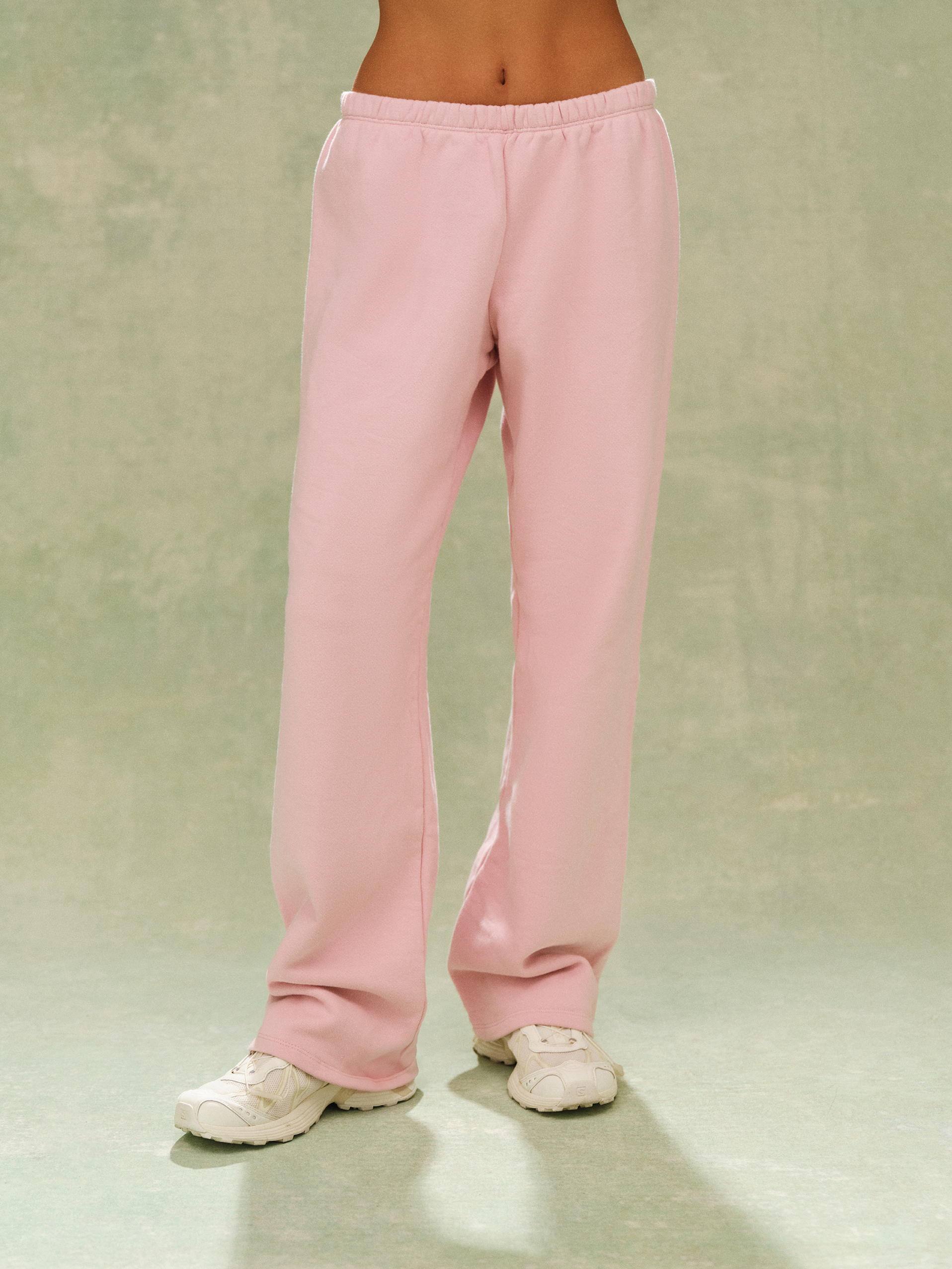 Pink sweatpants worn by a person on a plain background 