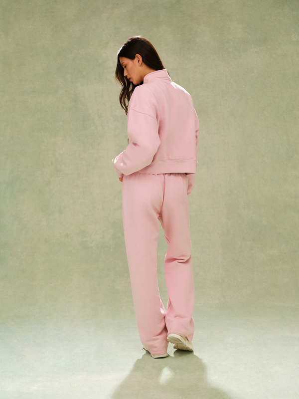Person wearing a pink tracksuit against a plain background