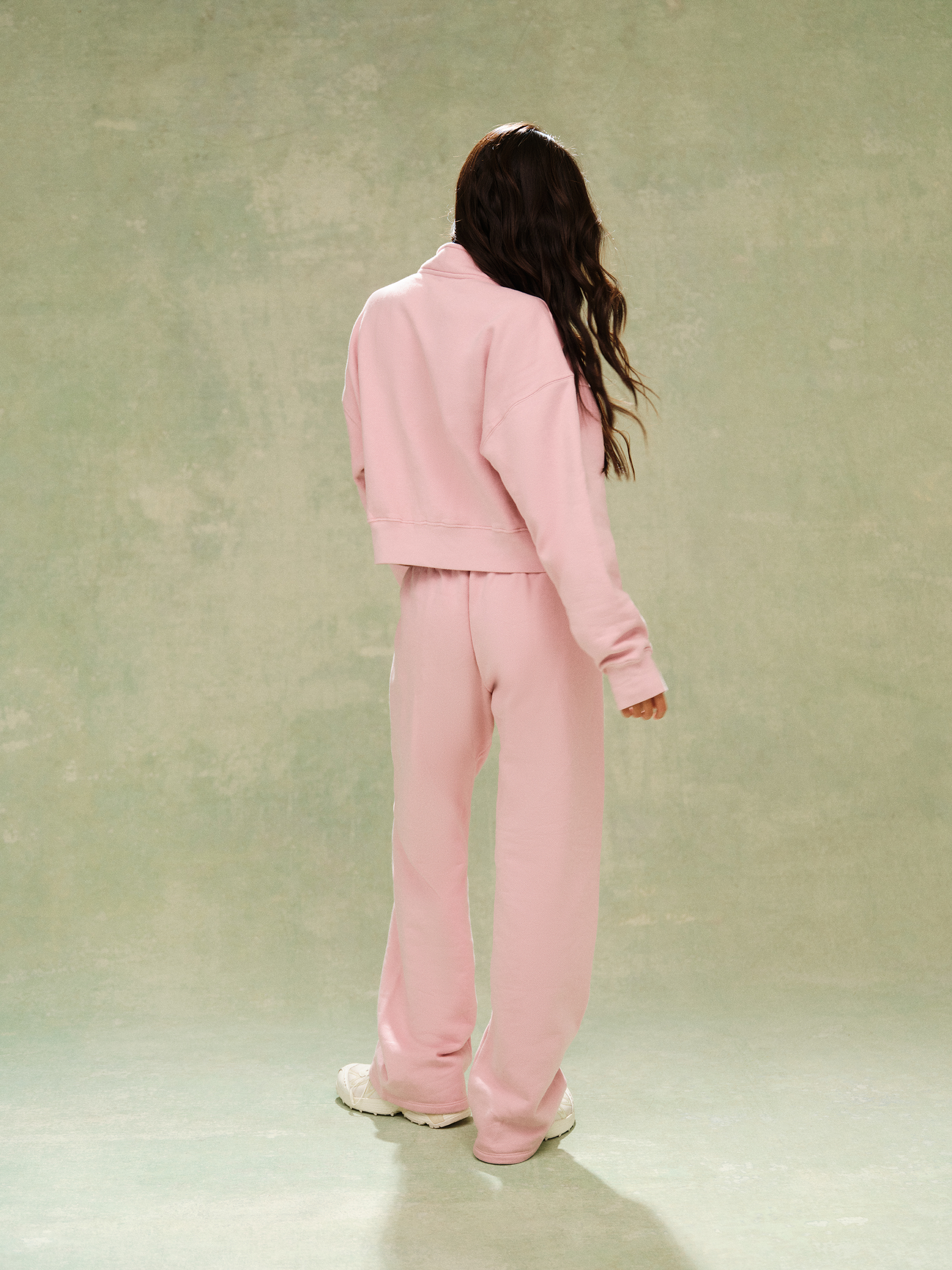Person wearing a pink tracksuit standing against a plain background