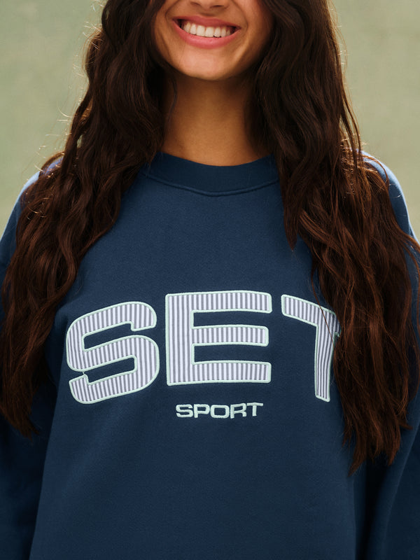 Person wearing a navy blue sweatshirt with 'SET Sport' logo