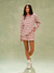 Woman wearing a pink and white striped dress against a plain background