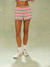 Person wearing a striped pink and white outfit with white sneakers on a light green background