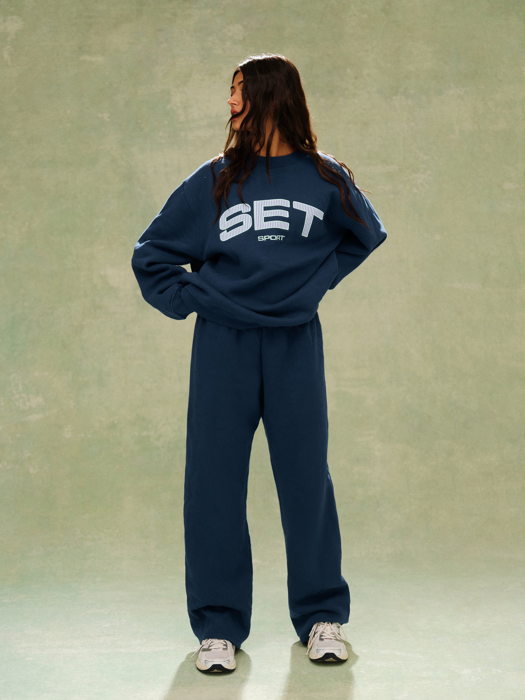 Person wearing a navy blue tracksuit with 'SET' logo on a plain background
