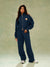 Person wearing a navy tracksuit with a logo on a plain background