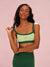 Woman wearing a green sports bra and leggings with a pink background <model-info>Sydney wears a size XS and is 5’9, 24½” waist, 32B bust.</model-info>