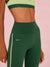 Green athletic leggings with a sports bra on a pink background