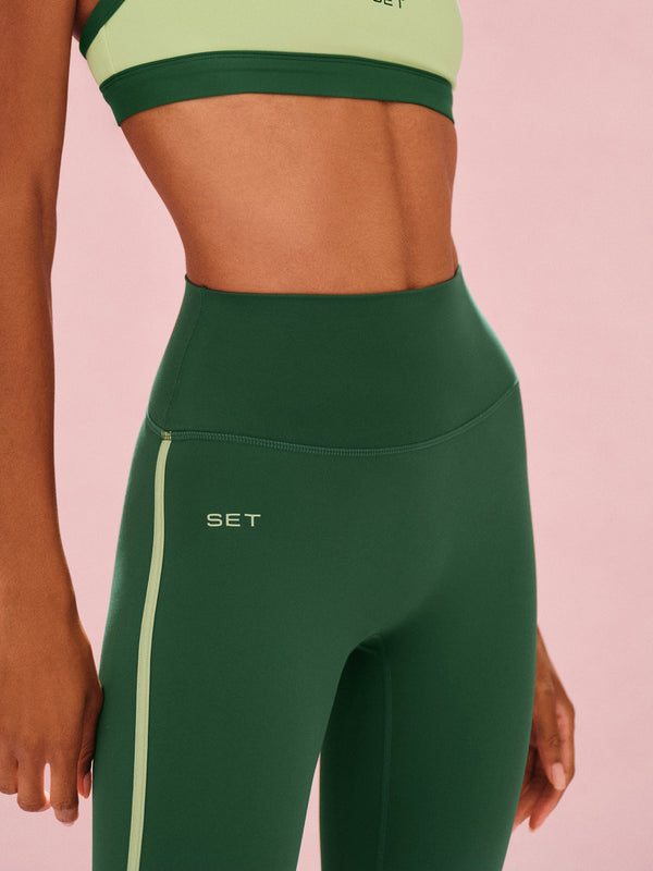 Green athletic leggings with a sports bra on a pink background
