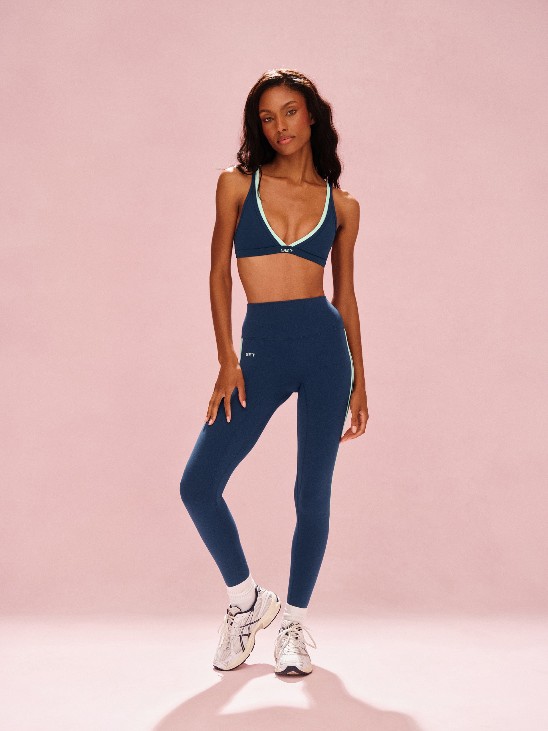 Woman wearing a blue athletic outfit on a pink background