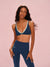 Woman wearing a navy sports bra and leggings set on a pink background