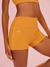 Yellow athletic shorts with a brand logo on a pink background 
