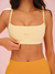 Woman wearing a light yellow sports bra with 'SET' branding on a pink background