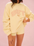 Person wearing a yellow sweatshirt with 'SET' printed on it against a pink background