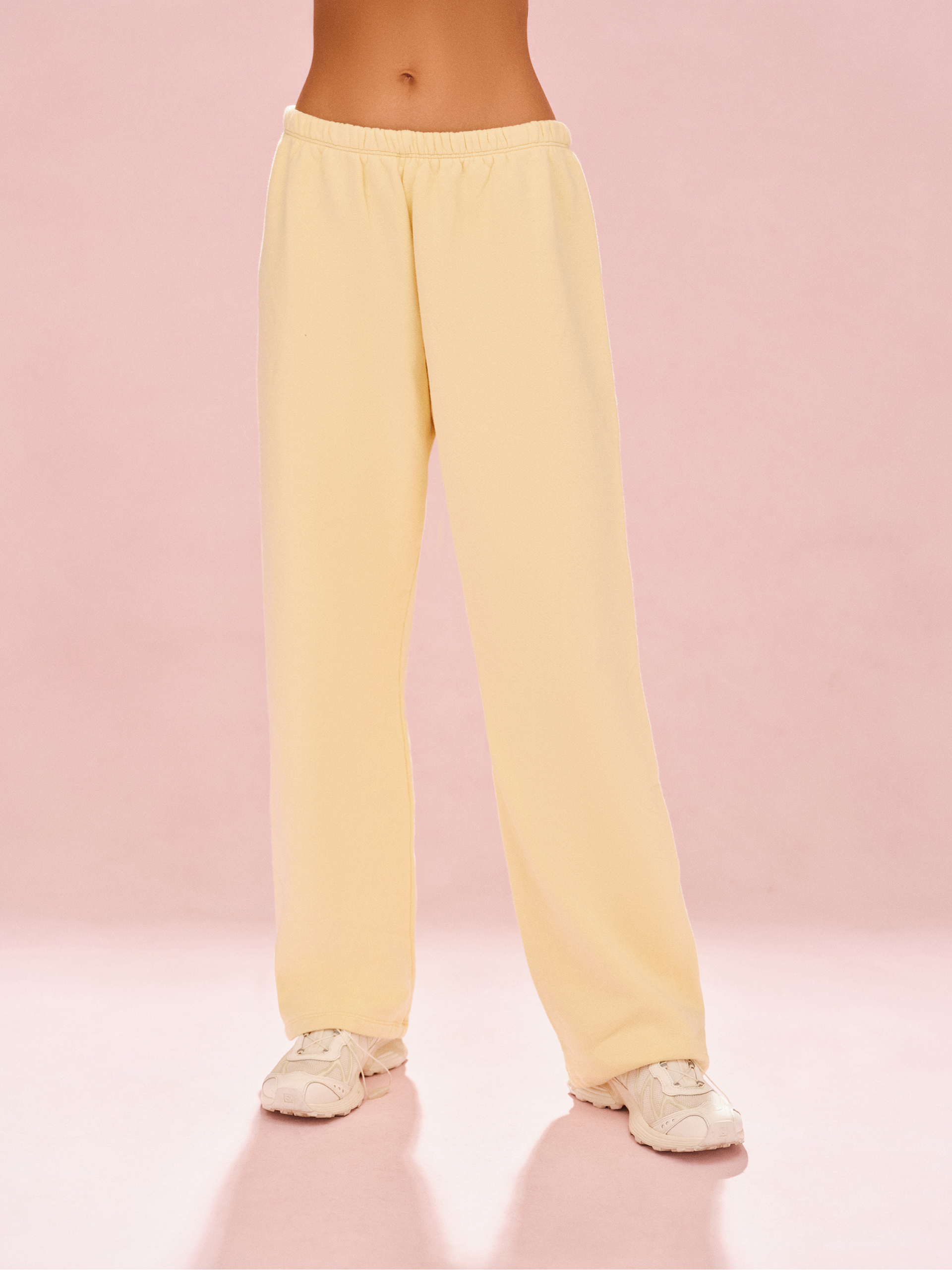 Person wearing light yellow sweatpants on a pink background <model-info>Meeya wears a size S and is 5’7, 23” waist, 32B bust.</model-info> 