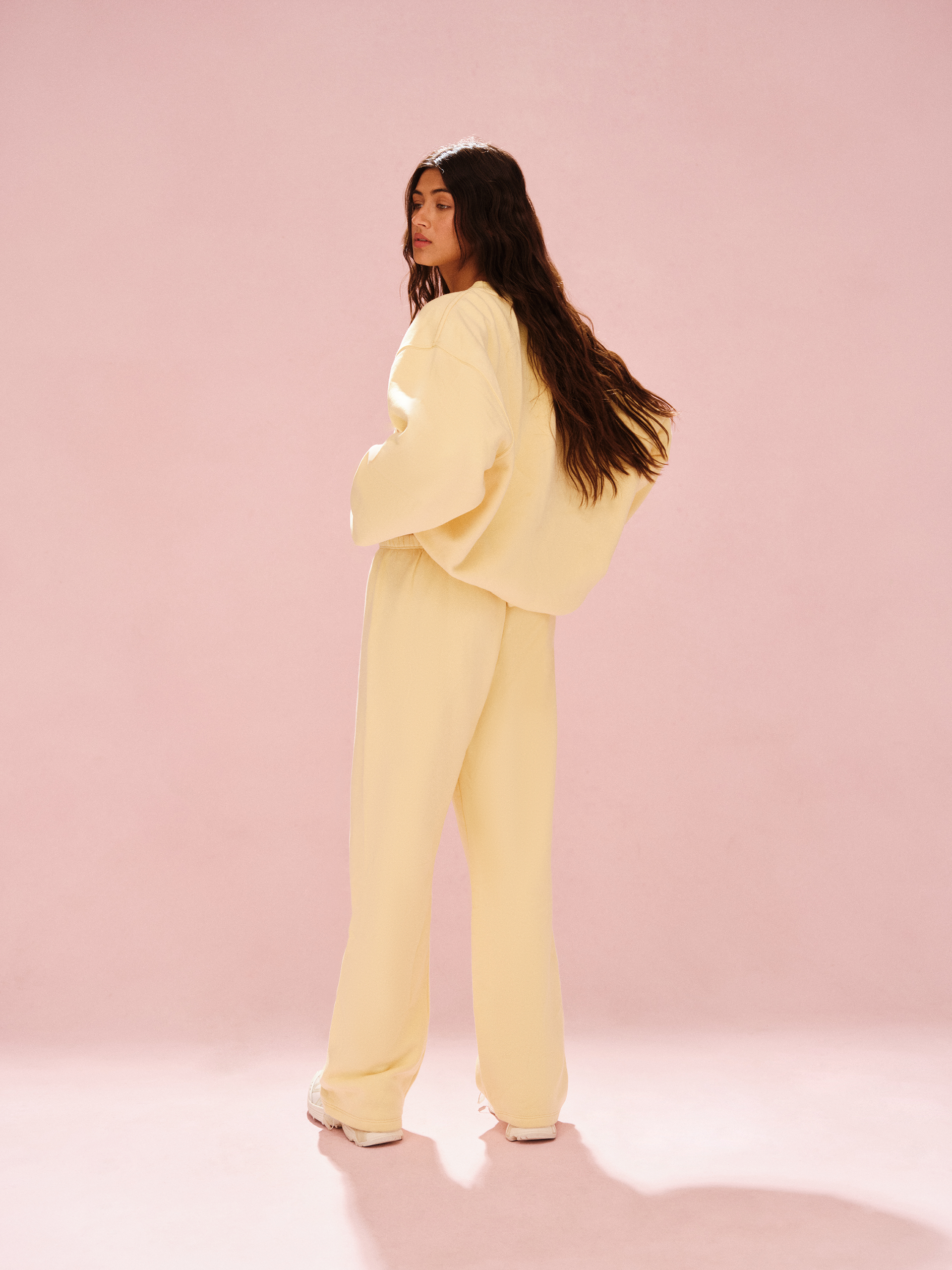 Person wearing a light yellow outfit against a pink background