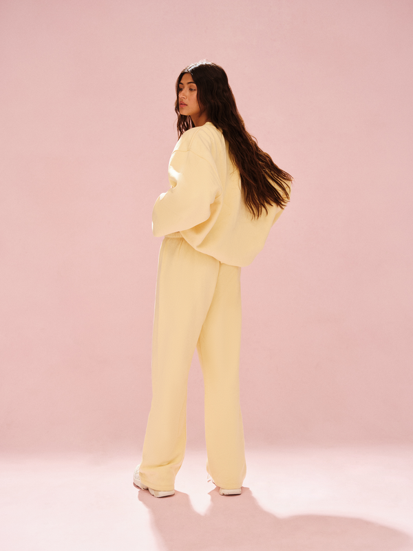 Person wearing a light yellow outfit against a pink background