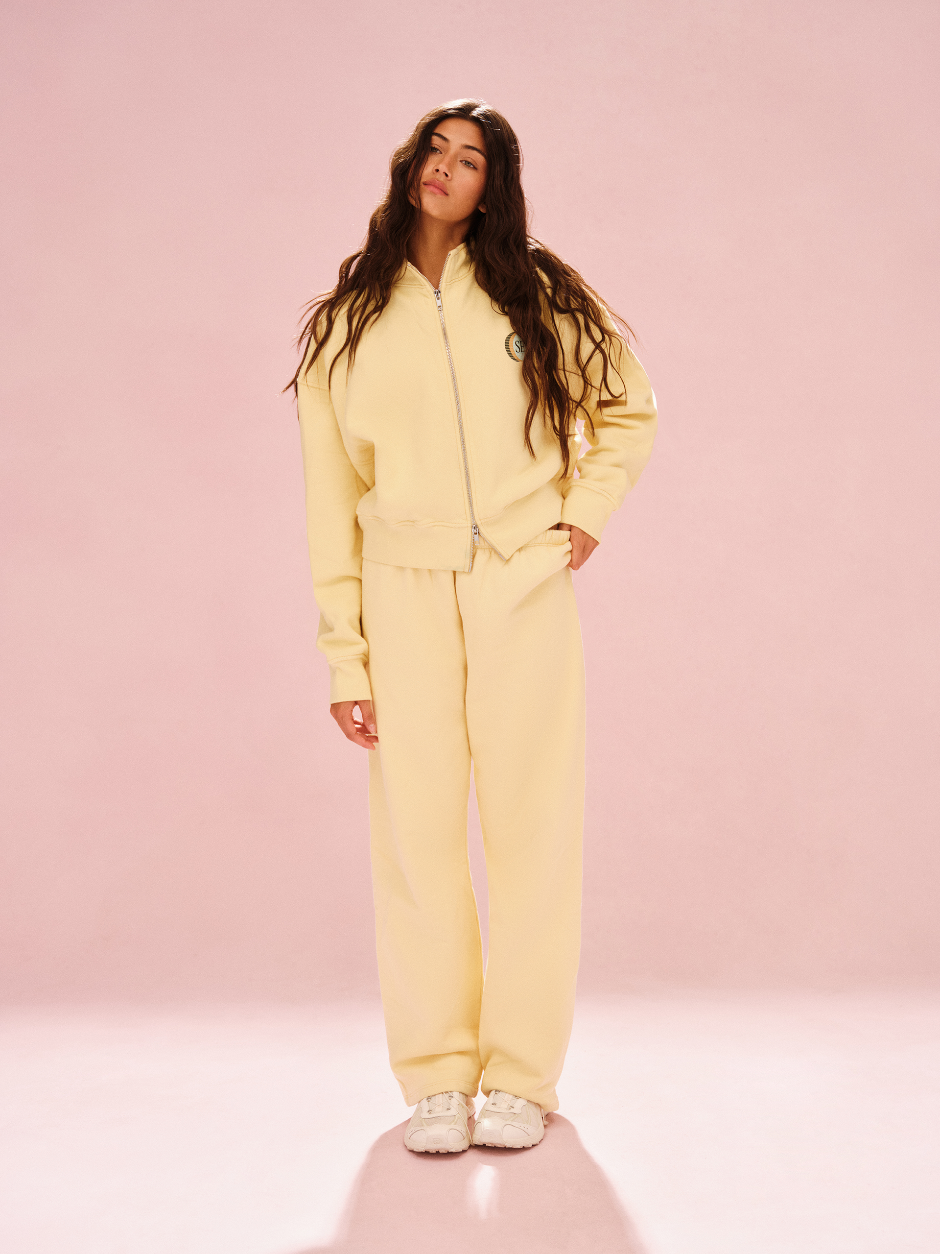 Woman wearing a yellow tracksuit against a pink background