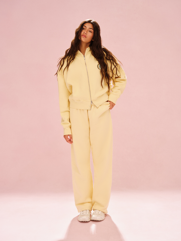 Woman wearing a yellow tracksuit against a pink background