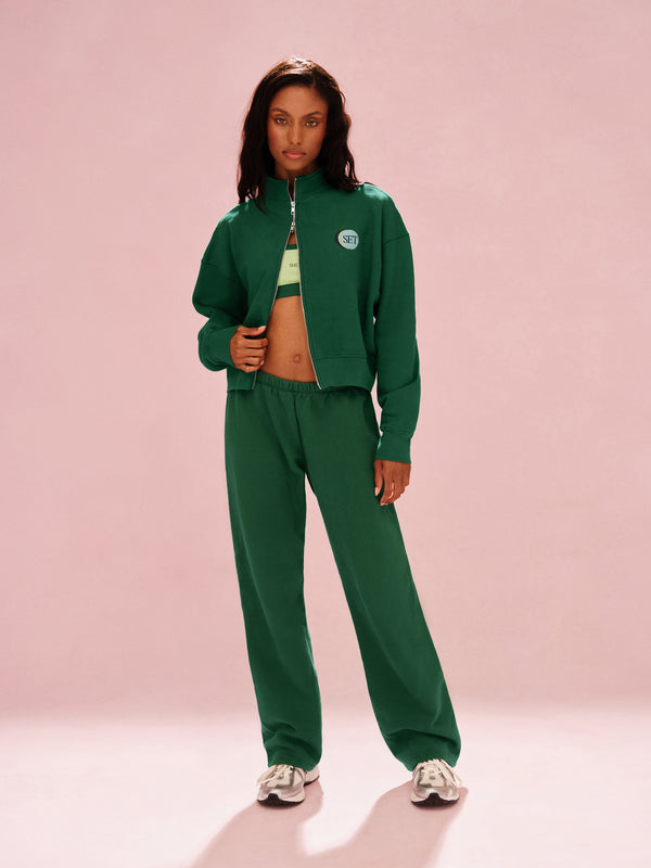 Person wearing a green tracksuit on a pink background