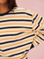 Close-up of a person wearing a striped shirt with yellow and navy horizontal stripes on a pink background.