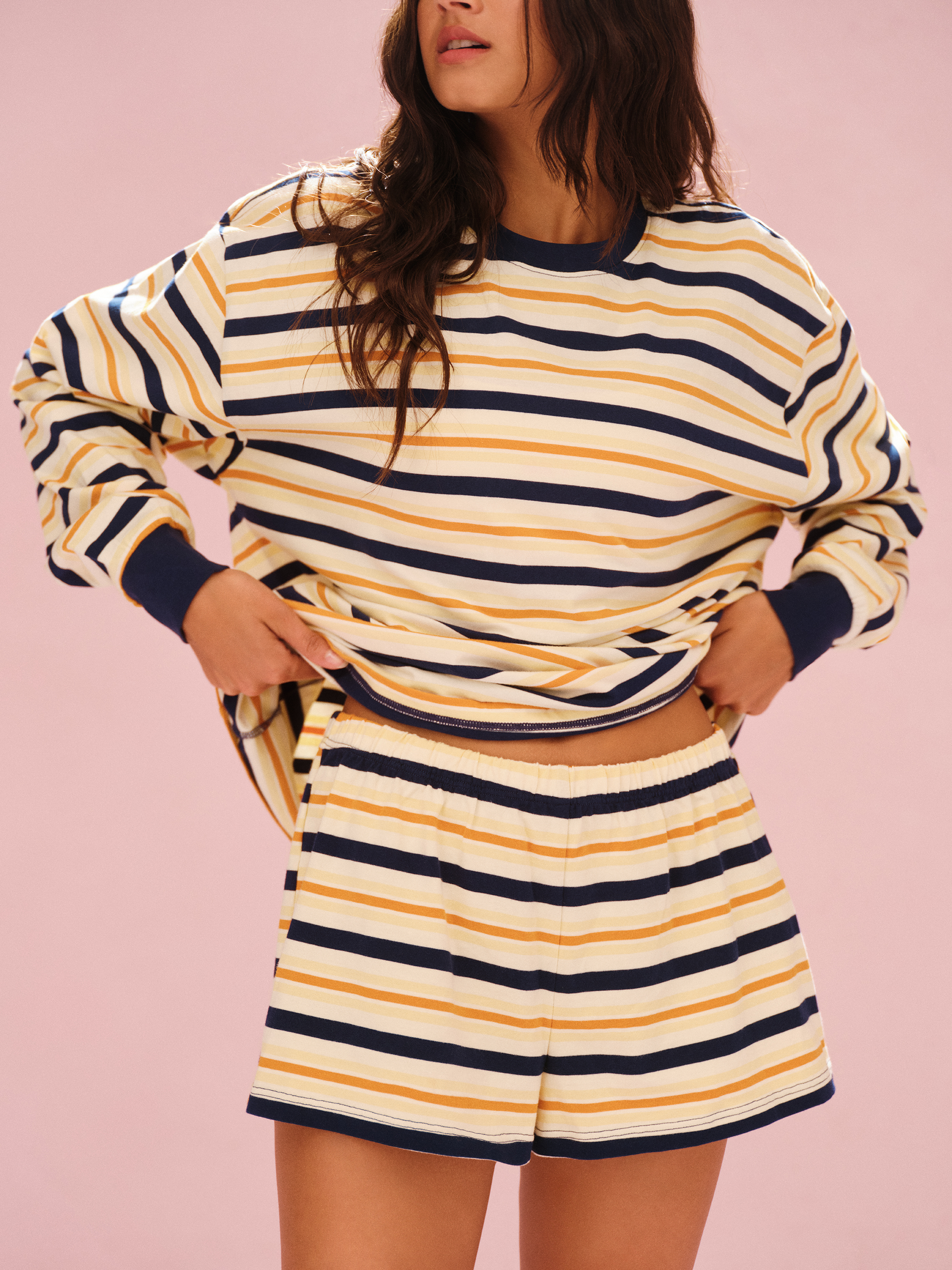 Woman wearing a striped pajama set on a pink background 