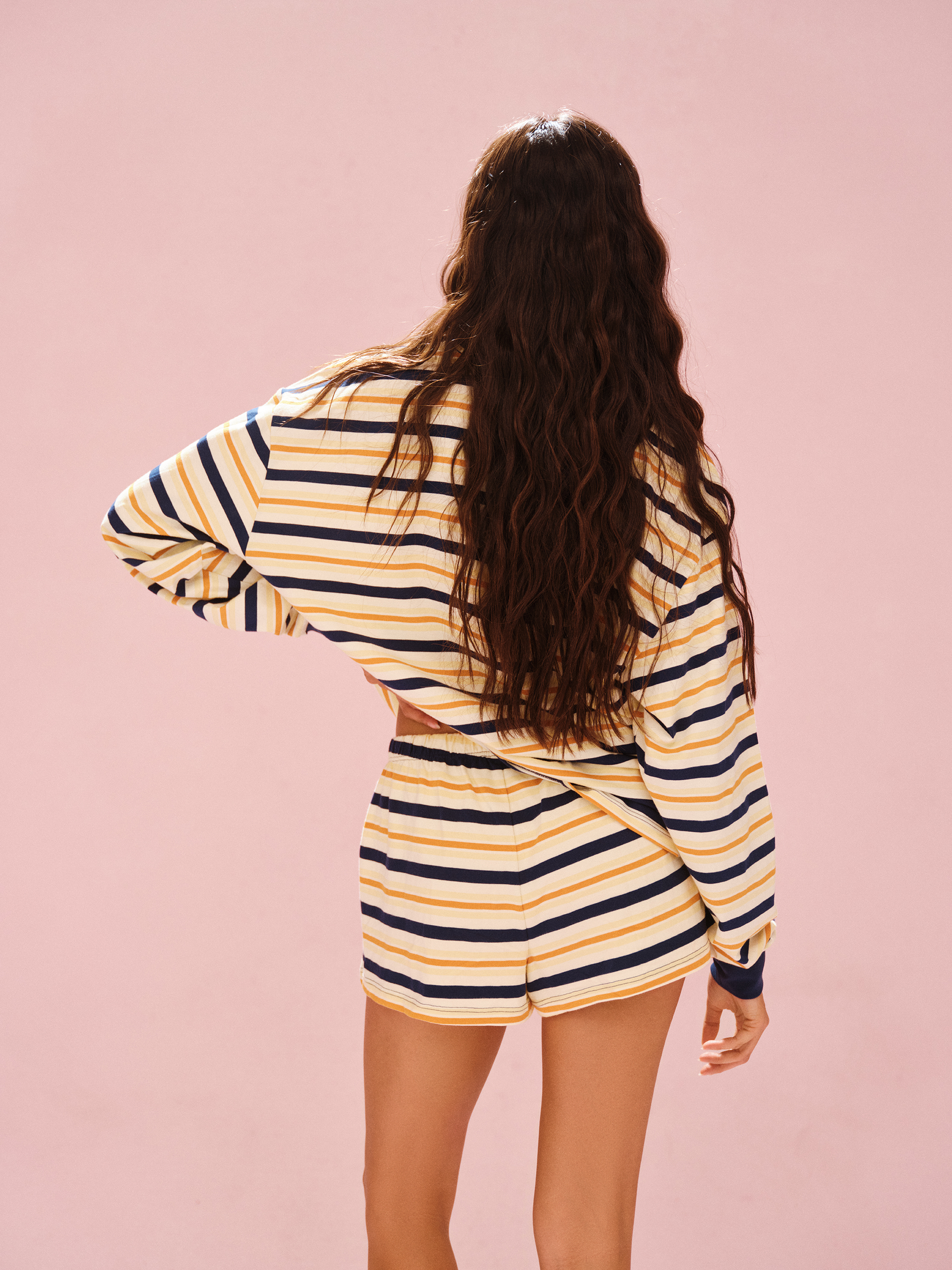 Person wearing a striped outfit on a pink background