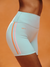 Light blue athletic shorts with pink accents on a person against an orange background <model-info>Sydney wears a size XS and is 5’9, 24½” waist, 32B bust.</model-info>