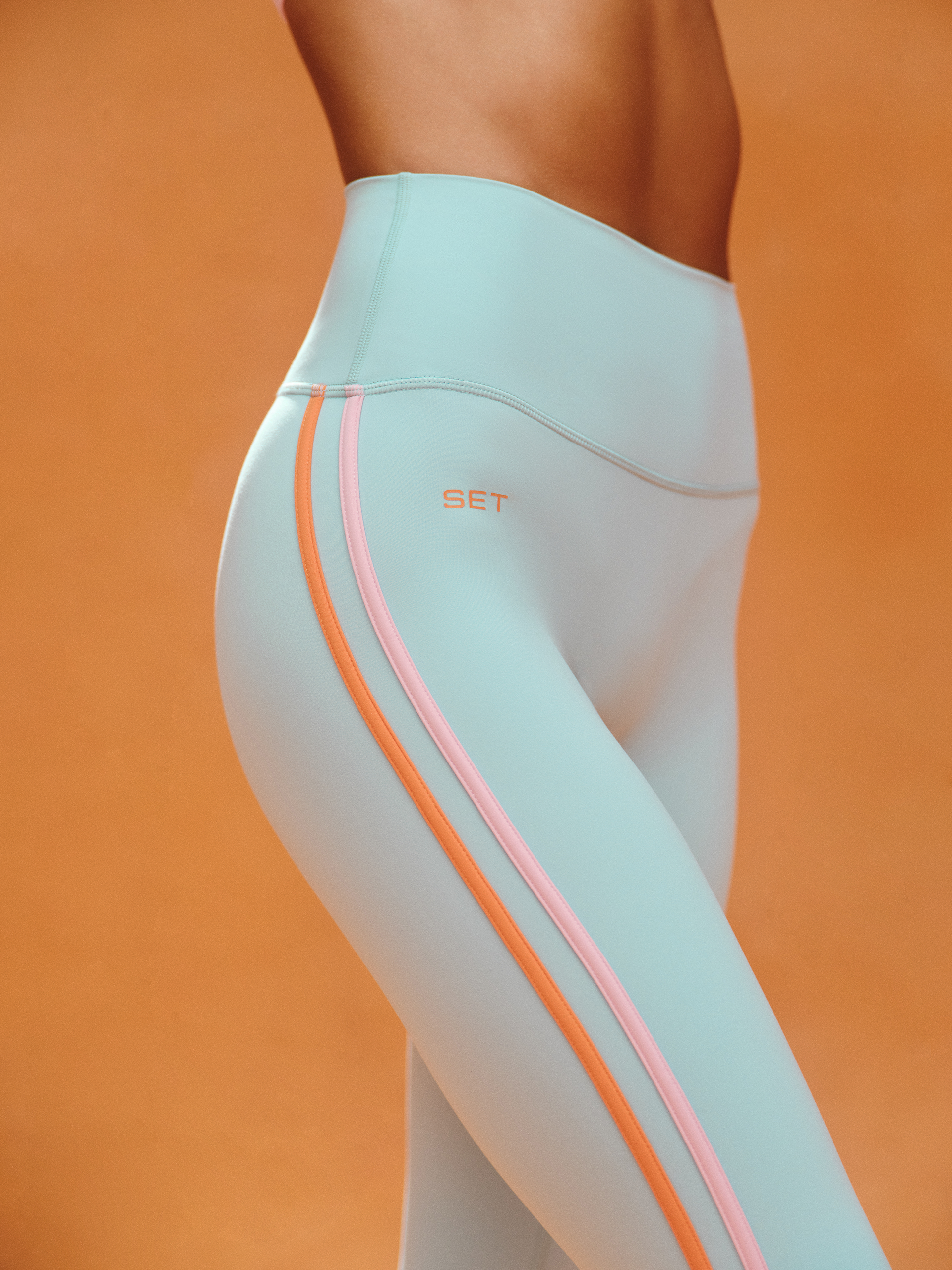 Light blue leggings with orange accents on a person against an orange background