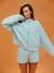 Woman wearing a light blue tracksuit with 'SET' branding on an orange background <model-info>Logan wears a size S and is 5’9½”, 24” waist, 32B bust.</model-info>