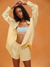 Woman wearing a light yellow outfit with a blue bralette against an orange background <model-info>Sydney wears a size XS and is 5’9, 24½” waist, 32B bust.</model-info>