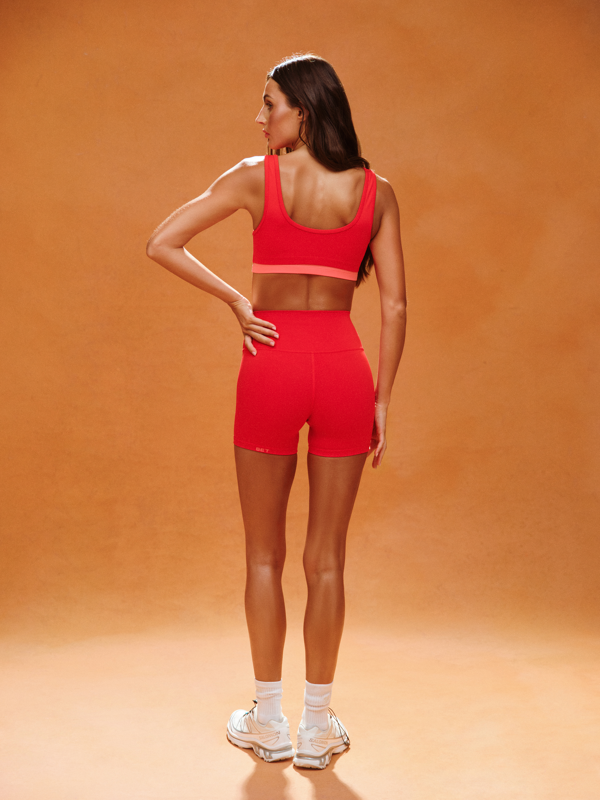 Woman wearing a red sports outfit on an orange background