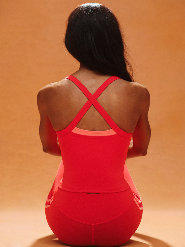 Person wearing a red athletic outfit with a cross-back design on an orange background