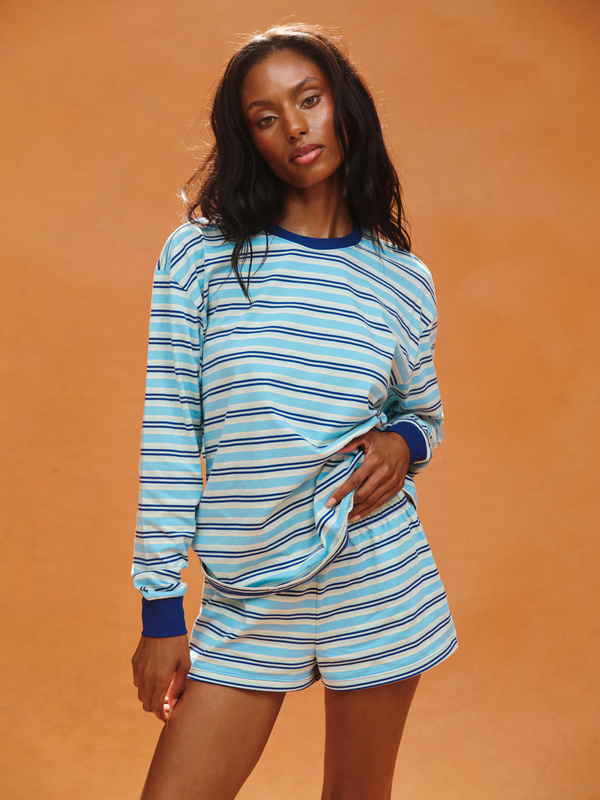 Woman wearing a blue and white striped outfit against an orange background 