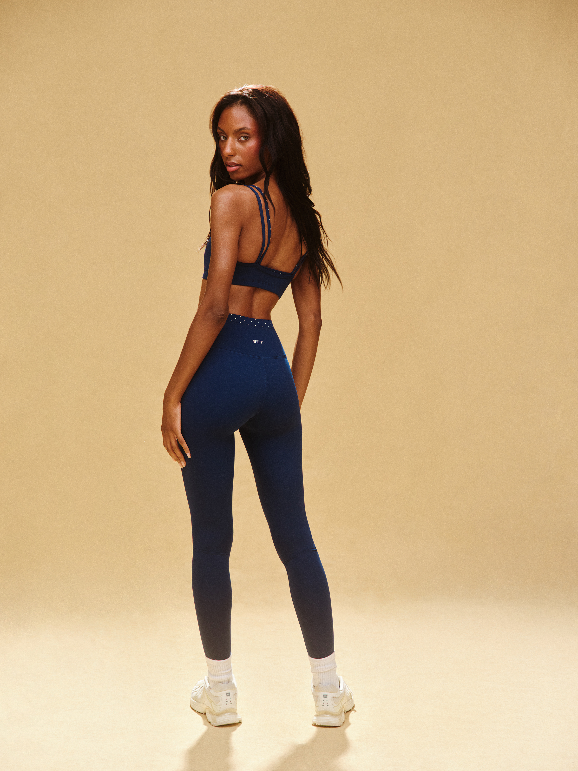 Woman wearing a blue athletic outfit on a beige background