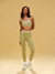 Woman wearing a green sports bra and leggings set on a beige background <model-info>Sydney wears a size XS and is 5’9, 24½” waist, 32B bust.</model-info>