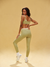 Woman wearing a green sports bra and leggings on a beige background