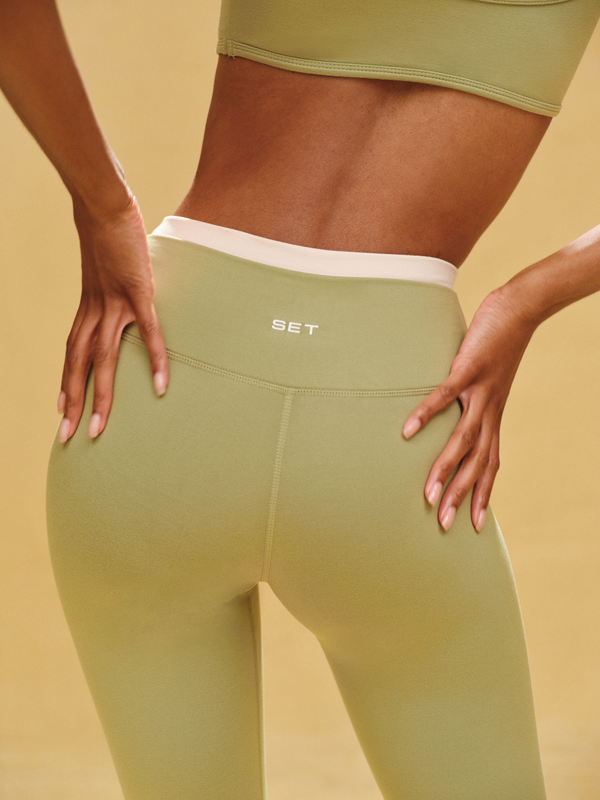 Green leggings with a visible brand logo on a beige background