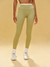 Person wearing light green leggings and white sneakers on a beige background