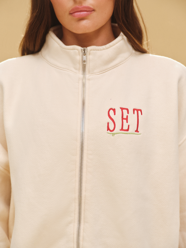 Beige jacket with 'SET' embroidered on the chest against a beige background