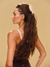 Woman with long hair styled in a high ponytail against a beige background