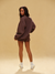 Woman wearing a brown sweatshirt and shorts set on a beige background