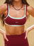 Person wearing a maroon sports bra and leggings with 'SET' branding on a beige background <model-info>Logan wears a size XS and is 5’9½”, 24” waist, 32B bust.</model-info>