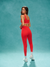 Woman in red athletic wear standing against a teal background