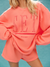 Person wearing a coral sweatshirt with 'SET RESORT' text on a teal background