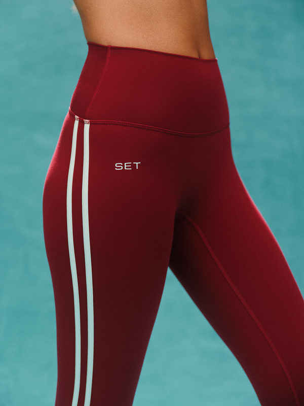 Maroon leggings with white stripes and 'SET' logo on a teal background
